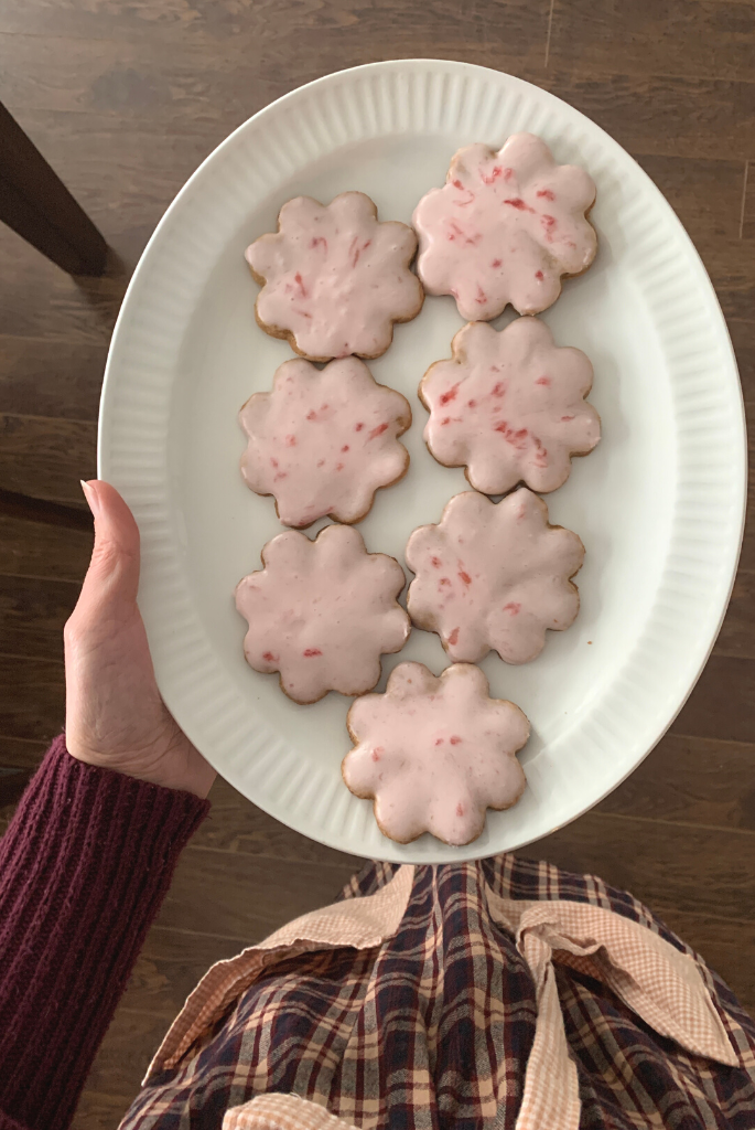 Holding Plate of Gluten Free Sugar Cookies Frosted with Homemade Strawberry Icing