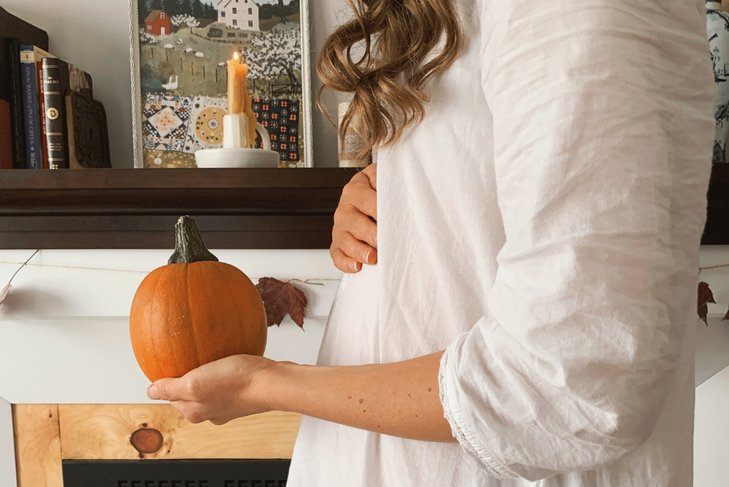 Fall pregnancy announcement photo with holding a pumpkin